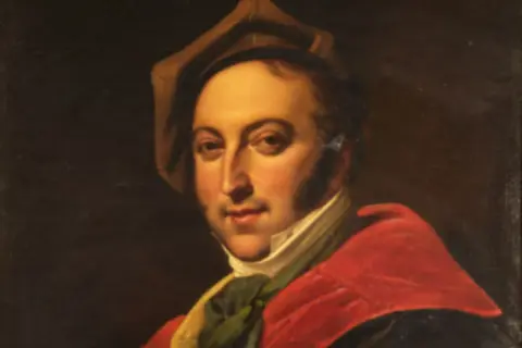 Portret Gioacchino Rossiniego w czerwonej todze i brązowym kapeluszu.